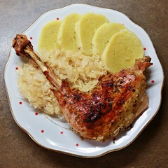Plate with typical Czech potato dumplings, stewed white cabbage and a piece of roasted turkey leg with a bone