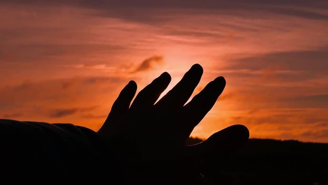 Sun's rays through fingers of male hand.