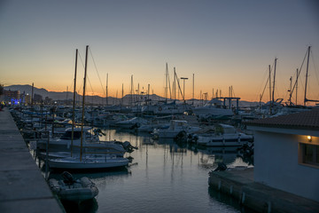 Fototapeta na wymiar Sunset view of a marina with sailing and motor boats and a mountainous landscape in the background