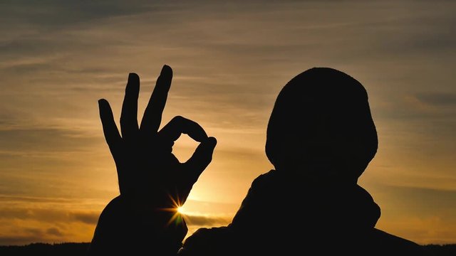 Silhouette ok hand on beautiful sunset background. OK symbol.