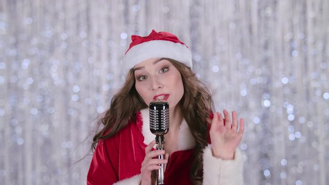 Snow maiden sings in a retro microphone and dances with energetic music. Bokeh background. Slow motion. Close up