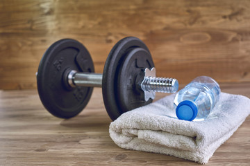 Fitness workout, slimming exercises, weight loss and diet healthy eating concept, dumbbells, bottle of mineral water and towel on wooden floor of training class