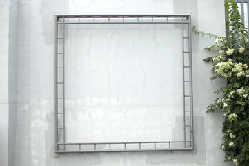 A metal frame against a white concrete wall outdoor