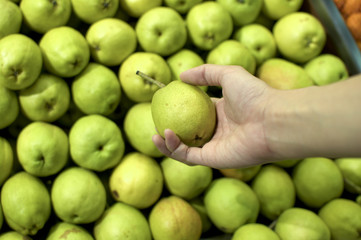 Holding a fresh green pear in the market