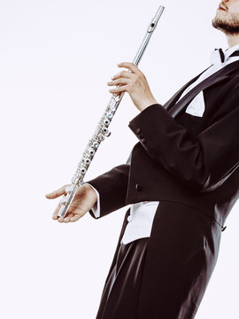 Male flutist wearing tailcoat holds flute