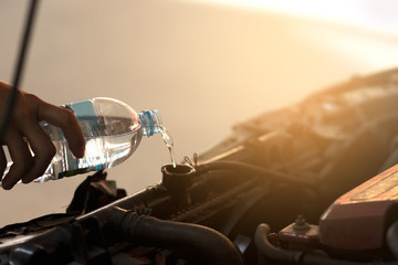 Hand pouring water for radiator in car. Because of the heat is due to some deterioration.