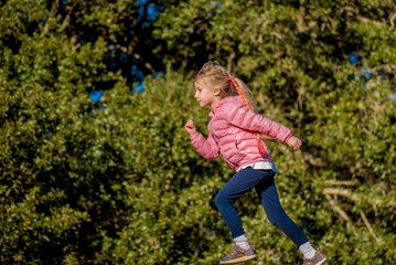 Little girl running on grassy hill in the park