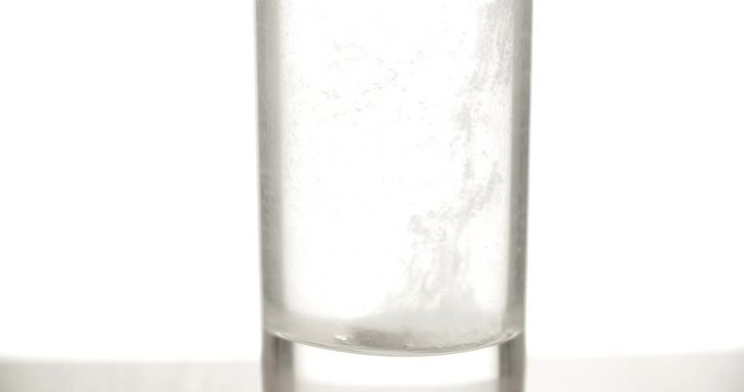 Effervescent aspirin tablet dropping to glass of water 4k video. Close up slow motion fizzy pill falls dissolves with bubbles. Medicine, health care pharmacy chemistry concept