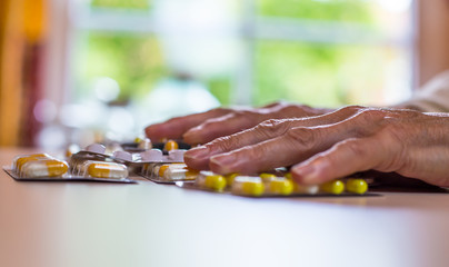 die Hände einer Frau und viele Medikamente liegen auf einem Tisch