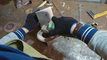 Craftsman using an angle grinder for polish metal detail at workshop.