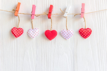 Valentine’s Day.  Sewed pillow hearts row border on red, pink and white clothespins at rustic white wood planks. Happy lovers day card mockup, copy space.  Valentine Concept