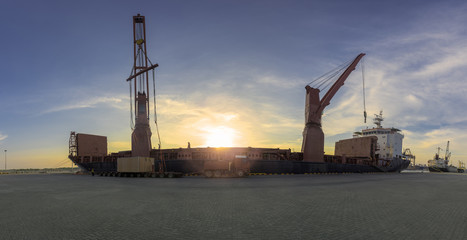 Fototapeta premium panorama of heavy lift, general cargo vessel alongside the jetty port terminal for discharging loading operation shipment