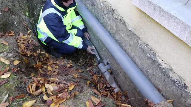 A woman plumber checks the horizontal position of the water pipes for fixing.