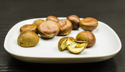 A cut ripe chestnut on a white plate on a table.