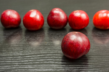 A ripe red plum, in the back row of plums.