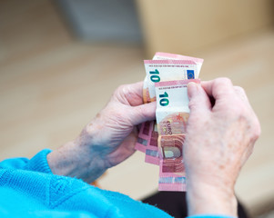 Rentnerin hält Euroscheine in der Hand