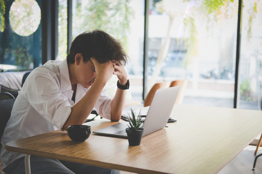 Student Using Computer For Learning Leasson Online At Cafe. Startup Man Working With Laptop At Office.  Young Male Entrepreneur Put Hand On Head Feeling Tired, Frustrated & Stressed At Workplace.