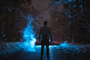 The man stand near the smoke in the winter forest. evening night time
