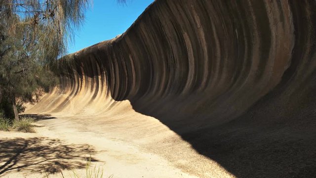 a tourist walks past the rock formation in western australia known as wave rock