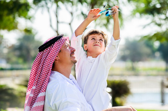 Arabic father and little kid play outdoors.