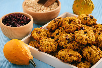 Pumpkin oatmeal cookies with cranberries on blue wooden background.
