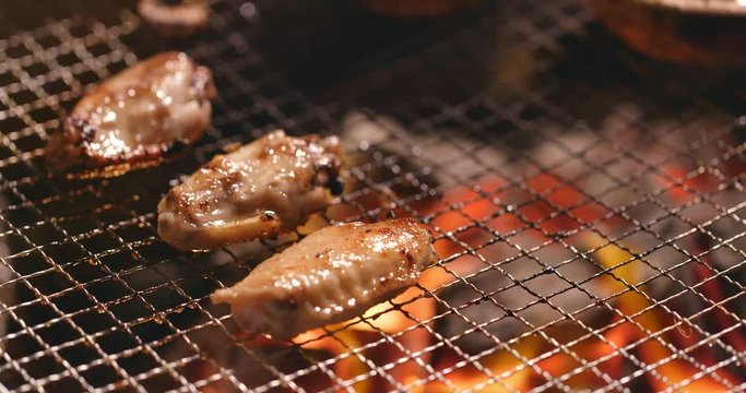 Barbecue with chicken wing, mushroom and capelin fish on grilled net at outdoor