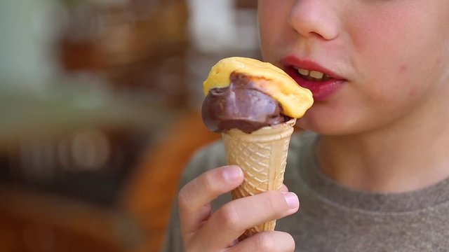 Closeup view of white cute little kid eating mixed ice cream at summer outdoors background.