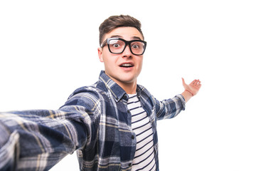 Portrait of a joyful casual man taking selfie and holding camera with hands over white