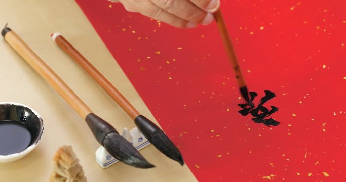 Writing Chinese calligraphy on write paper with phrase meaning happy new year