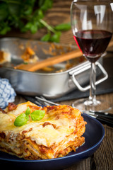 Piece of tasty hot lasagna with red wine.