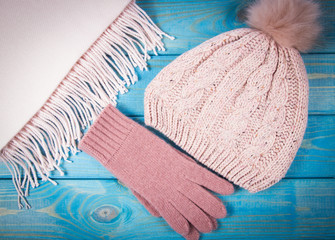 Warm winter knitted clothes - hat, scarf, gloves on a blue background.