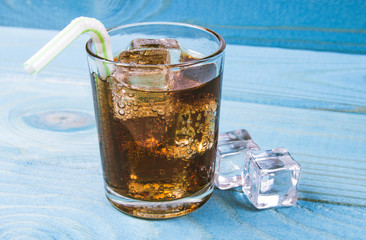 Sweet, fizzy drink with ice on a blue background.
