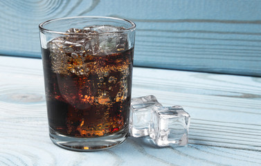 Sweet, fizzy drink with ice on a blue background.