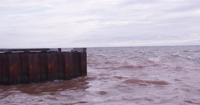 Red ocean water hitting steel wharf - slow motion