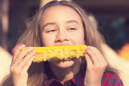 Girl eating sweet corn on the nature of the day