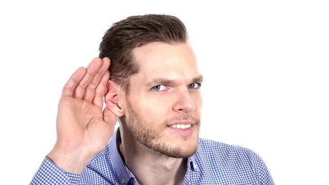 Handsome young man can't hear, putting hand around his ear 