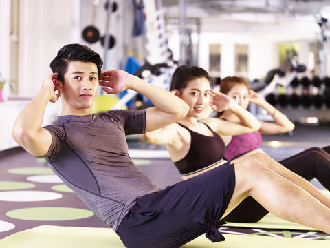group of young asian people exercising in gym