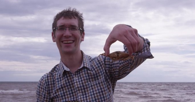 Young man holds crab on beach - close up
