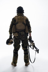 Full length soldier keeping modern weapon while turning back to camera. Army concept