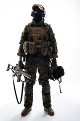 Fototapeta premium Full length portrait of serious peacemaker holding helmet and modern weapon in arms. Army concept