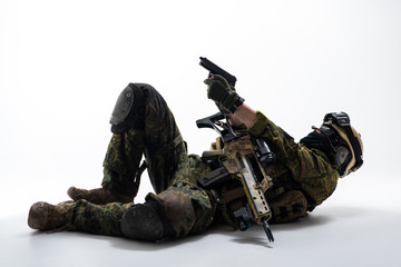 Full length side view serious defender shooting with gun while lying on floor. Military concept