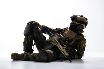 Full length side view calm soldier having rest. He keeping assault rifle in arms. Relax and work concept