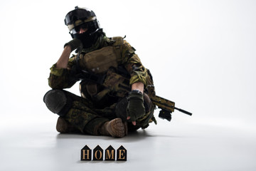 Portrait of serious defender wearing uniform while sitting on ground. He missing home. Army concept