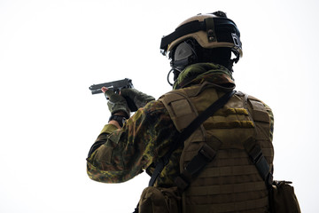Soldier in army uniform shooting with pistol. He turning back to camera. Army concept. Isolated and...