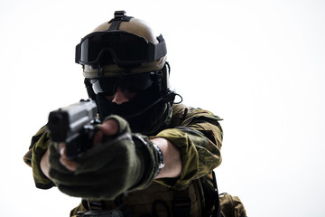 Portrait of strong soldier in balaclava and helmet shooting with pistol. Profession concept....