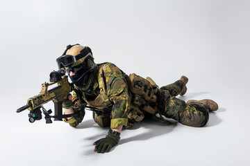 Full length portrait of calm defender watching at weapon while situating at floor. Military concept