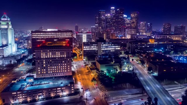 Cinematic urban aerial view of downtown streets with city skyline at night