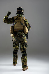 Full length man wearing ammunition while flourishing arm. He turning back to camera. Military concept