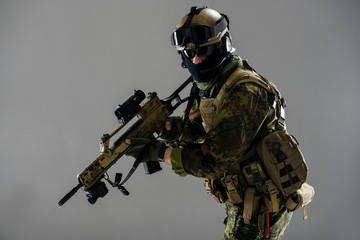Portrait of stern soldier with helmet and balaclava holding weapon in arms. He looking at camera. Warfare concept. isolated