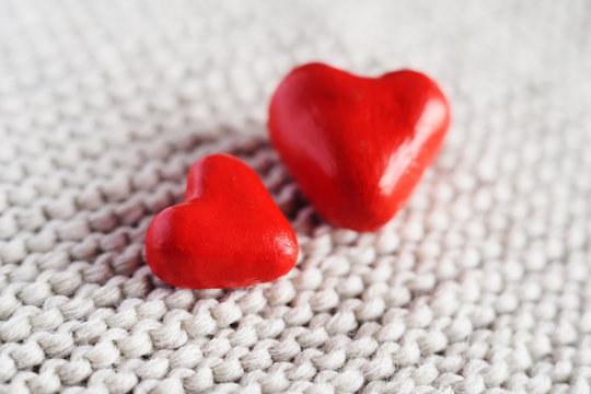 two red hearts on knitted background.
